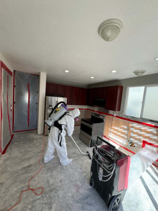 Technician repairing a kitchen water leak and drying cabinets in a Parker, Colorado home
